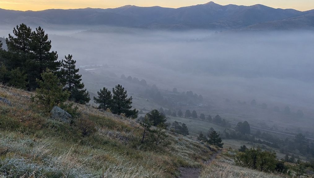 Smoke pooled low in a valley at first light while the ridge above it stays clear